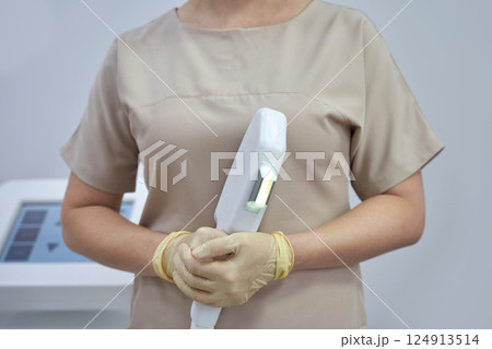 Female technician holding laser hair removal device in clinic setting 124913514