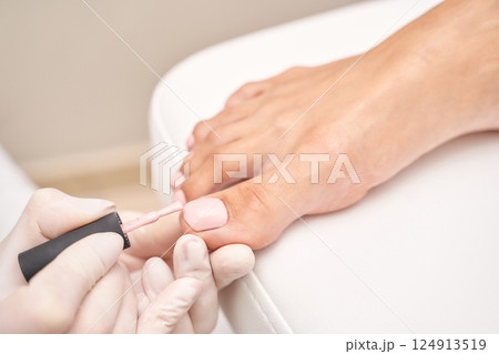 Female pedicure with pink nail polish on caucasian feet in salon Female pedicure with pink nail polish on caucasian feet in salon 124913519
