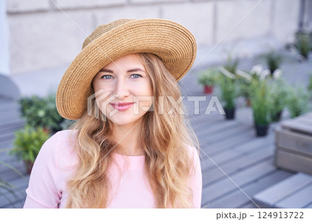 Young caucasian woman in straw hat smiling outdoors surrounded by plants Young caucasian woman in straw hat smiling outdoors surrounded by plants 124913722