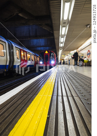 London Underground train arriving at platform with yellow line safety warning 124913728