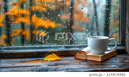 White mug with a book and a leaf on a table 124914982