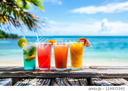 Four colorful drinks are lined up on a wooden table by the ocean 124915342