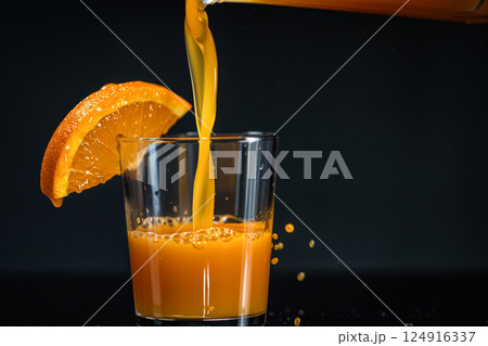 Glass of orange juice is poured into a glass. 124916337