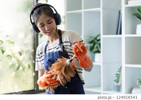 Smiling cleaner with headphones dusting in bright office 124916541