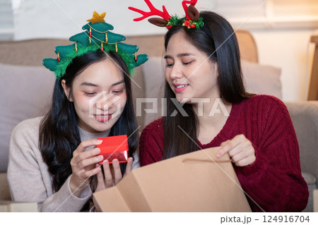 Lesbian couple sharing Christmas joy with thoughtful gifting Lesbian couple sharing Christmas joy with thoughtful gifting 124916704