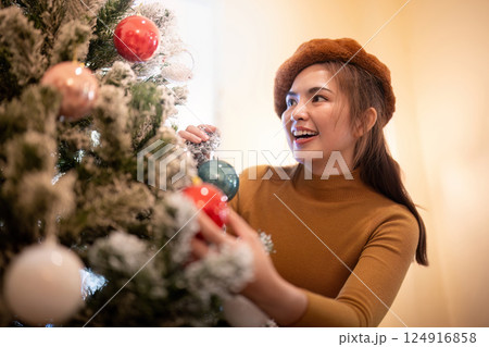 Excited Christmas Tree Decorator Adding Ornaments to Celebrate the Festive Season 124916858