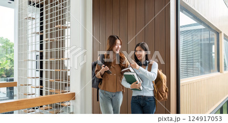 Friendship and Education. Two students walking together in a university setting, sharing academic insights. Friendship and Education. Two students walking together in a university setting, sharing academic insights. 124917053