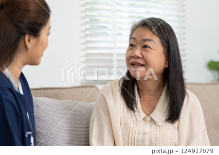 Caregiver and Patient Interaction. A caregiver and a senior woman engaging in a warm conversation during a home visit. Caregiver and Patient Interaction. A caregiver and a senior woman engaging in a warm conversation during a home visit. 124917079