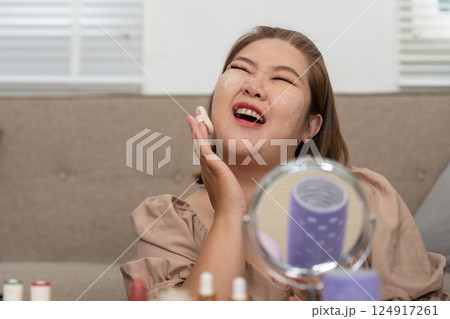 Skincare and Self-Care. A woman applying moisturizer while enjoying her beauty routine. 124917261
