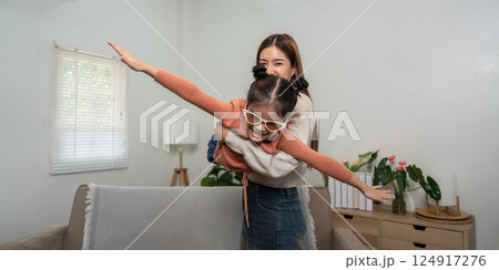 Family Interaction and Playfulness. A mother lifts her daughter, depicting joy and anticipation for their journey. 124917276