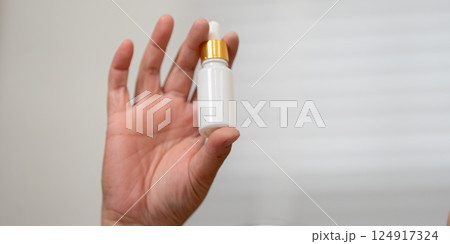 Serum and Skincare and Personal Care. A hand holding a beauty serum dropper, highlighting the essentials of skincare in a beauty routine. Serum and Skincare and Personal Care. A hand holding a beauty serum dropper, highlighting the essentials of skincare in a beauty routine. 124917324