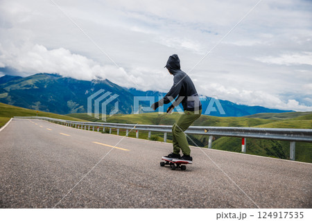 Skateboarder skateboarding on the mountain road 124917535