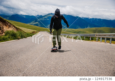 Skateboarder skateboarding on the mountain road 124917536