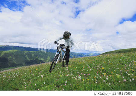 Riding mountain bike on flowering grassland mountain top 124917590