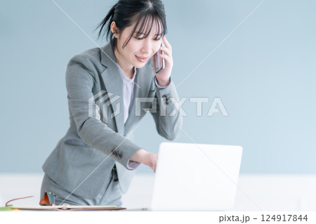 スマホで資料を確認しながら通話する若いキャリアウーマン 124917844