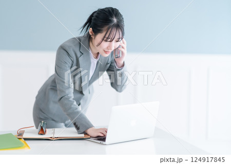 スマホで資料を確認しながら通話する若いキャリアウーマン 124917845