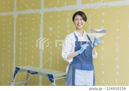 石膏ボードにパテをする女性　 124918154