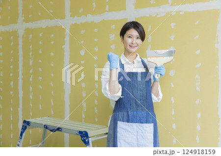 石膏ボードにパテをする女性　 124918159