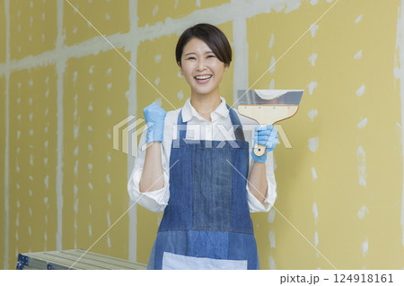 石膏ボードにパテをする女性　 124918161