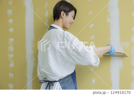 石膏ボードにパテをする女性  石膏ボードにパテをする女性  124918170