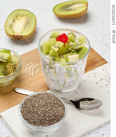Yogurt and chia seed pudding in a glass, kiwi pieces. White table Yogurt and chia seed pudding in a glass, kiwi pieces. White table 124918530