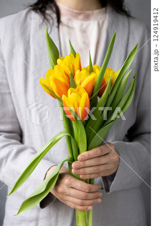 woman holds bouquet of yellow-red tulips in her hands. a birthday or mother's day gift.  124919412