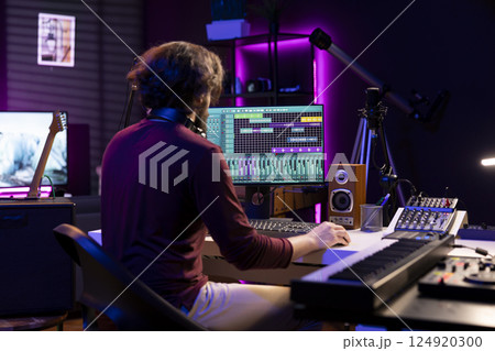 Sound engineer working in his home studio with daw software on computer and mixing tools, creating music. Producer mixing and mastering soundtracks, signal processing acoustical engineering. 124920300
