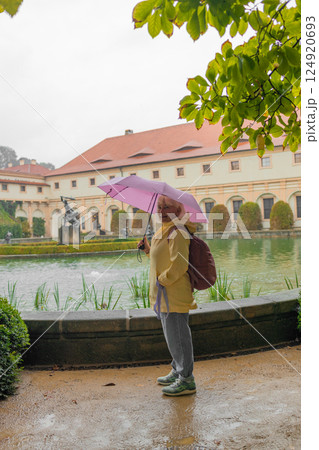 A female tourist walks around along a decorative alley decorated with many statues in a decorative park at Wallenstein Palace building in Prague in Czech Republic 124920693