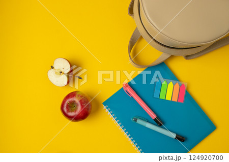 Colorful Office Supplies with Notepad, Pens, and an Apple on Yellow Background Colorful Office Supplies with Notepad, Pens, and an Apple on Yellow Background 124920700