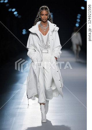 A Fashion Model Gracefully Walking in an Elegant Attire on the Runway and Showcasing Style. The woman presents a trendy total white look 124921506