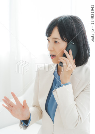 身振り手振りで通話先の相手と話をするミドルキャリアウーマン 124921943
