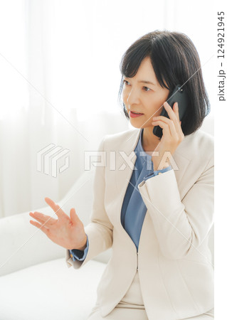 身振り手振りで通話先の相手と話をするミドルキャリアウーマン 124921945