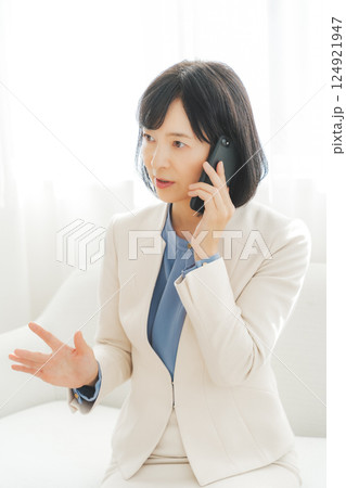 身振り手振りで通話先の相手と話をするミドルキャリアウーマン 身振り手振りで通話先の相手と話をするミドルキャリアウーマン 124921947