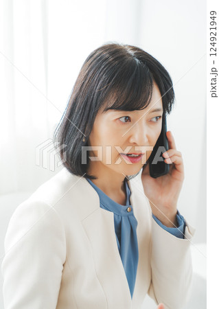 身振り手振りで通話先の相手と話をするミドルキャリアウーマン 身振り手振りで通話先の相手と話をするミドルキャリアウーマン 124921949