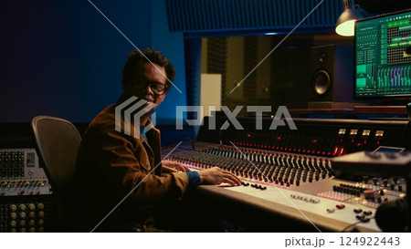Music producer operating mixing console in control room and working with audio recording software on pc, post production. Sound engineer editing tracks to produce new songs. Camera B. 124922443