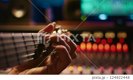 Musician singer recording a new song on his electro acoustic guitar, creating new music in professional studio control room. Artist doing live performance with instrument. Close up. Camera B. Musician singer recording a new song on his electro acoustic guitar, creating new music in professional studio control room. Artist doing live performance with instrument. Close up. Camera B. 124922448