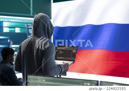 Propagandist person in a Russian cybersecurity center with the national flag works on installing fear and anxiety among the population by manipulation and brainwashing, cyber conflicts. Propagandist person in a Russian cybersecurity center with the national flag works on installing fear and anxiety among the population by manipulation and brainwashing, cyber conflicts. 124922583