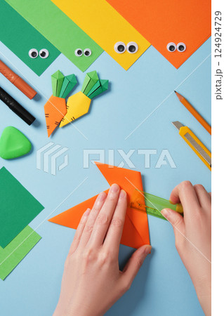 Making origami carrot. DIY project. Bend the corners of the triangle toward the center. Making origami carrot. DIY project. Bend the corners of the triangle toward the center. 124924729