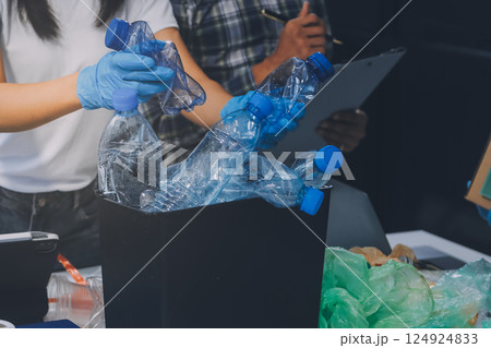 Close-up of female hands from a family collecting plastic waste and bottles from the ground. They wear gloves and focus on recycling to help reduce plastic pollution and protect the environment. Close-up of female hands from a family collecting plastic waste and bottles from the ground. They wear gloves and focus on recycling to help reduce plastic pollution and protect the environment. 124924833