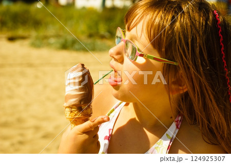 Toddler girl eating ice cream on beach Toddler girl eating ice cream on beach 124925307