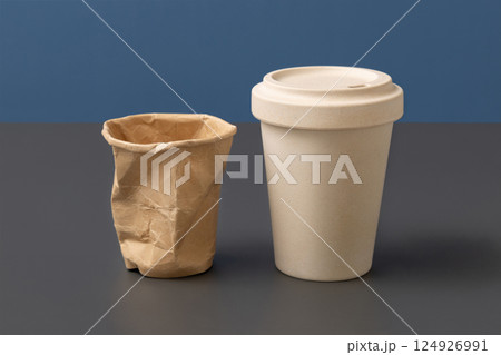 Used disposable paper cup and reusable bamboo coffee cup closeup, copy space, mockup 124926991