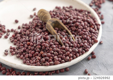 Plate full of dried red azuki beans with a wooden scoop closeup. East Asian legumes, vegetarian food 124926992