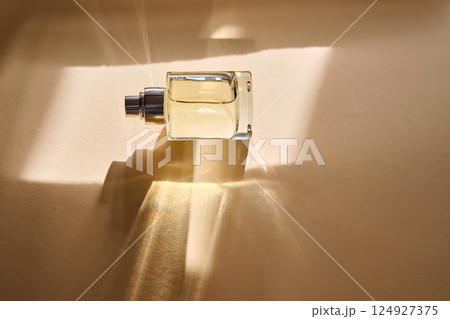 Perfume on a beige background in the rays of bright sun with beautiful highlights. Perfume on a beige background in the rays of bright sun with beautiful highlights. 124927375