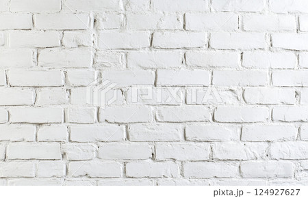 A white-painted brick wall with distinct textures and horizontal alignment, giving a clean yet rustic aesthetic. 124927627