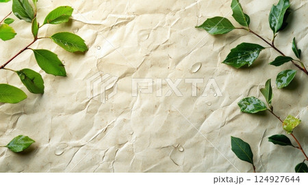 Green leaves with water drops framing wrinkled beige paper background 124927644