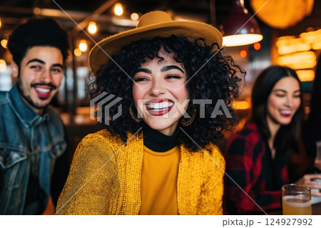 Young woman wearing a hat smiling with friends at a brewery 124927992