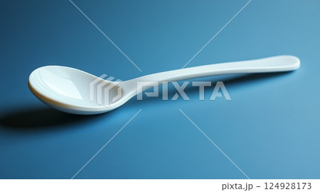 White ceramic spoon lying on a blue tablecloth 124928173