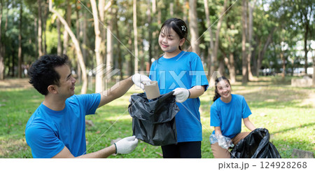 Engaged family participating in a joyful garbage collection day in a lush park 124928268