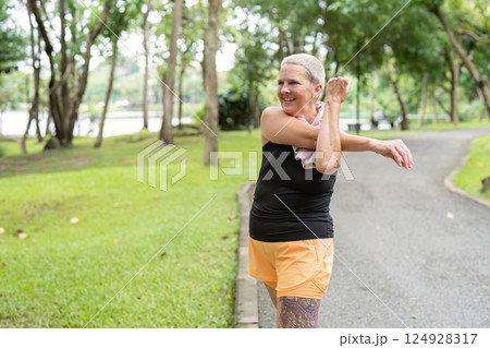 Elderly woman stretching her arms before a jog in a scenic park Elderly woman stretching her arms before a jog in a scenic park 124928317