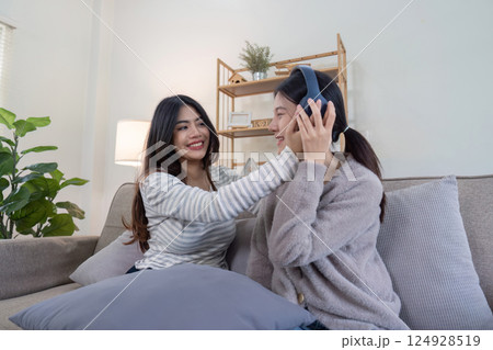 Joyful lesbian couple enjoying music together at home intimate lifestyle moment cozy environment warm atmosphere 124928519